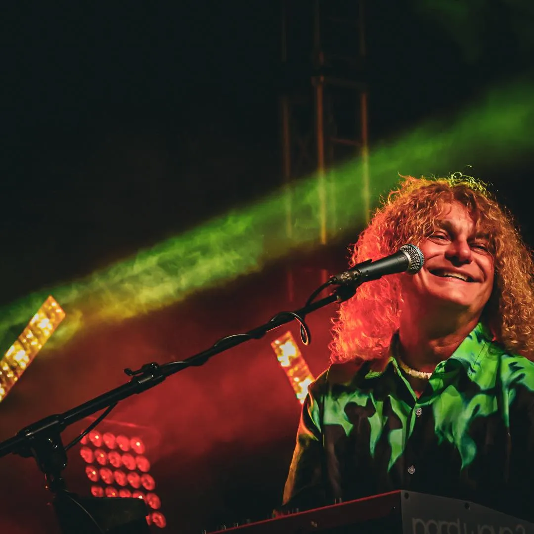The keyboard player singing under green and red stage light