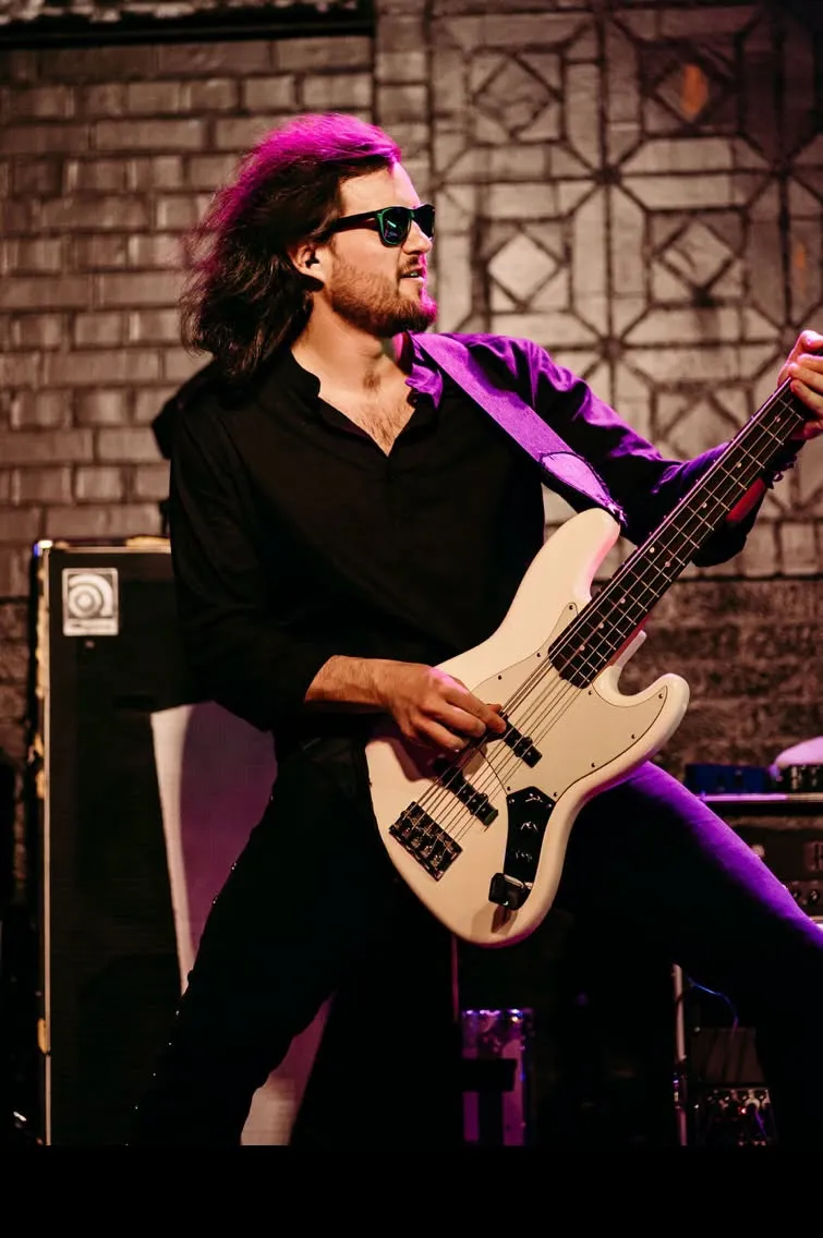 The bass player in sunglasses under purple stage light