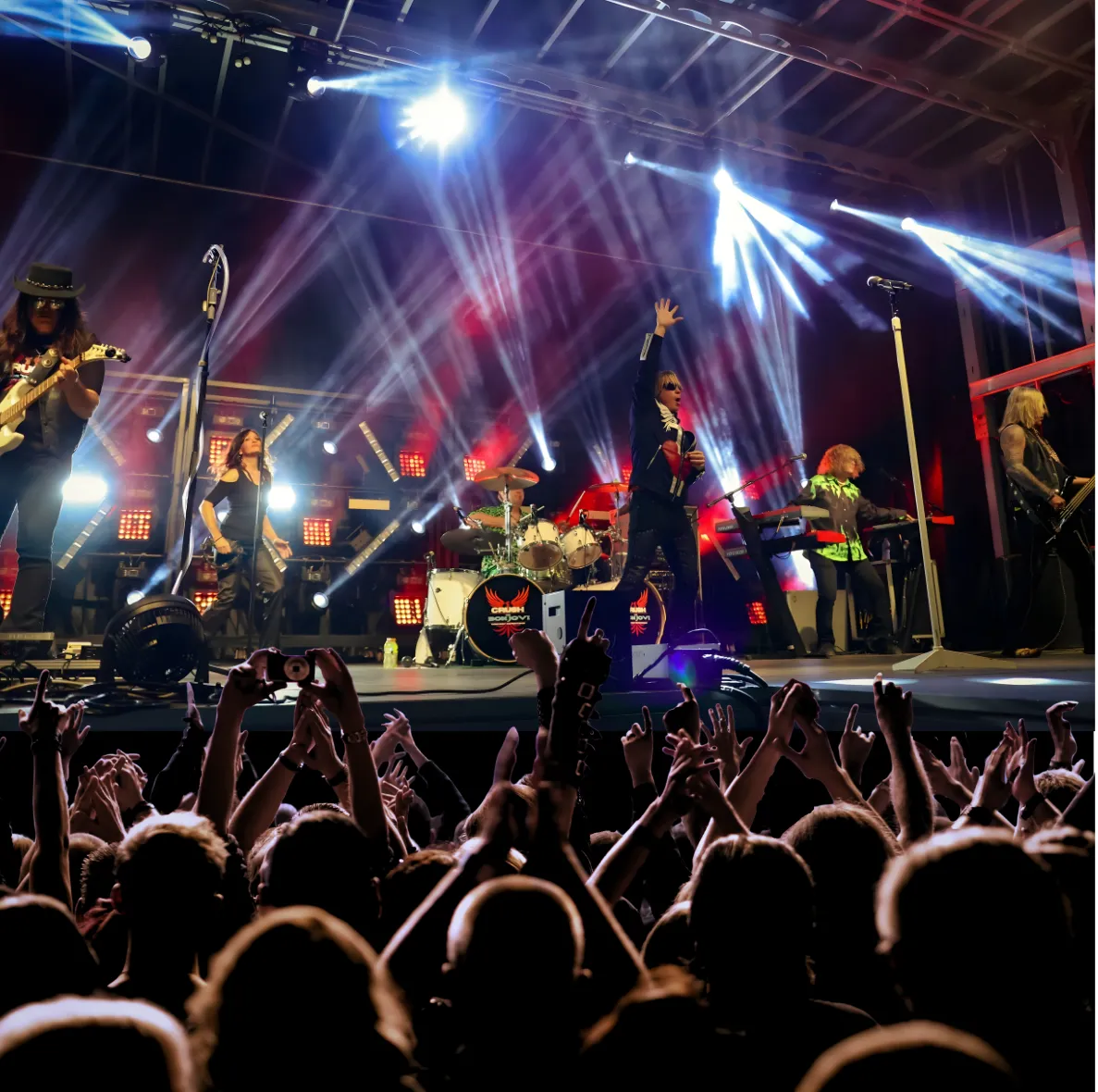 The full stage in white light beams with hands raised across the front row